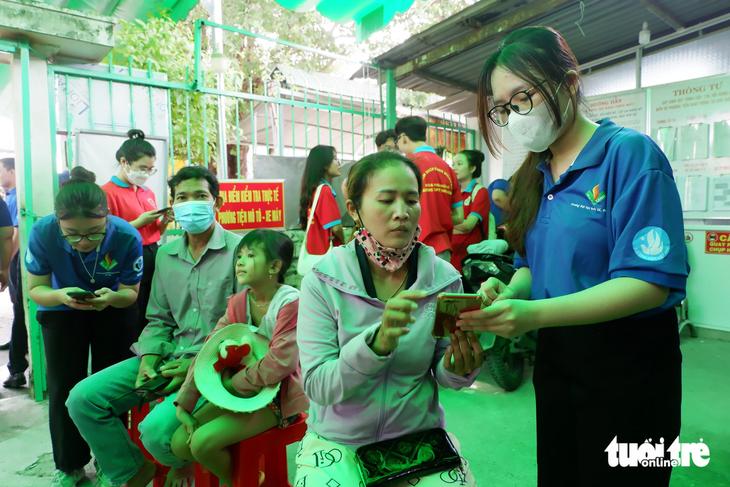 Sinh viên hỗ trợ người dân tại huyện Bình Chánh, TP.HCM khi đến cài đặt mã định danh điện tử - Ảnh: K.ANH