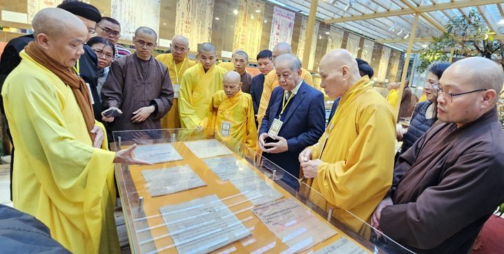 Các văn bản có chữ của các chúa Nguyễn được thượng tọa Thích Không Nhiên (bìa trái) giới thiệu với mọi người - Ảnh: THÁI LỘC